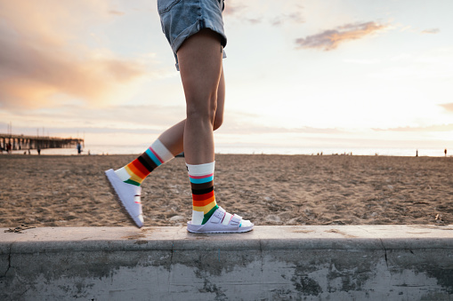 Person wearing rainbow socks during the Pride Month walking by the beach in California, United States.