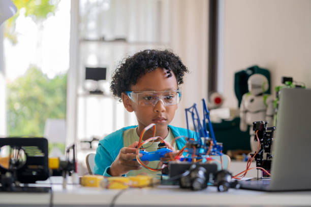 istock A young black child is deeply engaged in writing coding to control a mechanical arm in his living room. Engaging in online e-learning with expert teachers, the child demonstrates curiosity, creativity, and a passion for STEM topics. 2148162976