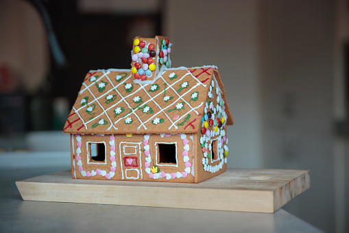 colourfully decorated gingerbreadhouse on board in a kitchen