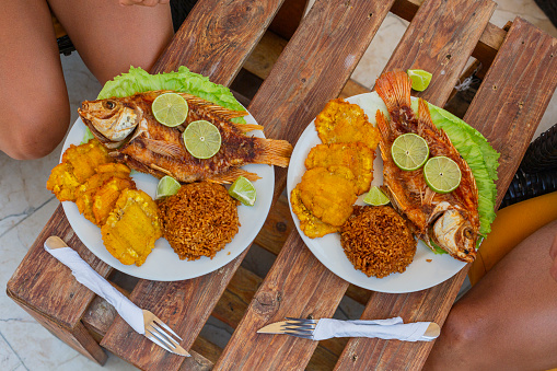 dishes of typical food from Cartagena, fried fish, salad and patacon served at the clients' table