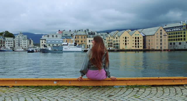 Woman Relaxing at Harbour of Alesund City Admiring Scenic Views
