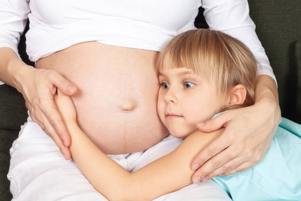 istock Wonderstruck Child Embracing Expectant Mothers Belly 2148165533