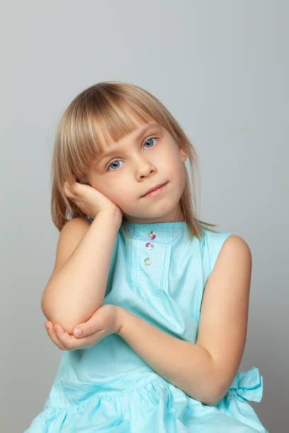 istock Little girl resting her head on hand against a grey background 2148165834