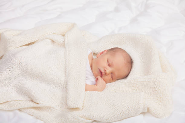 istock Newborn Baby Asleep Wrapped in Knit Blanket 2148166047