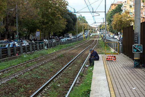 Italy, Rome: a lonely man, sitting on the platform of the Torpignattara train station, waits for the train