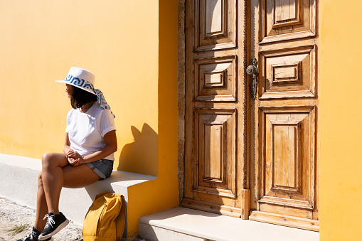 Woman with hat sitting on a beautiful street in the old town of Rhodes on her visit to the Greek city