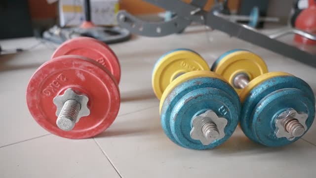 Orbit motion close up of the colored heavy adjustable dumbbell set lying on the floor in the living room. Home gym equipment