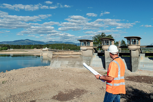 Maintenance engineer looking at blueprints in dam
