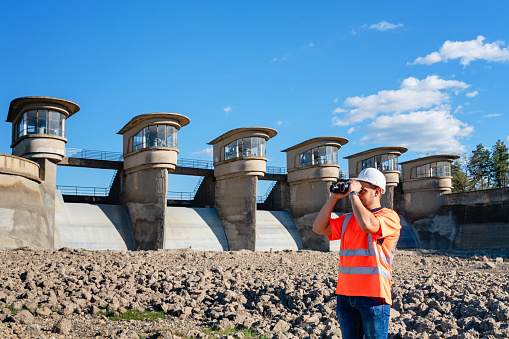 Male engineer standing in drying lake or dam during summer heat wave
