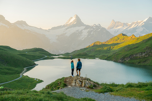 Man and woman looking at Bachalpsee lake in Swiss Alps in summer in the morning