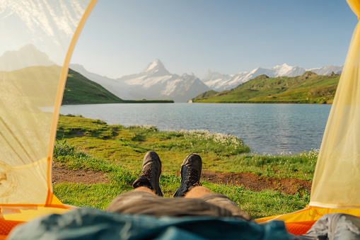 POV of man  laying in the tent and looking at lake in Swiss Alps in summer