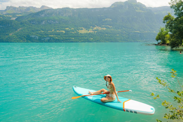 Serene scene of woman SUP boarding on lake in Alps in summer