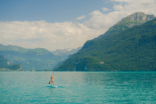 Serene scene of woman SUP boarding on lake in Alps in summer