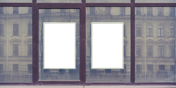 Two blank advertising spaces framed borders with white space for mockup in urban setting. Reflection of classic architecture in window panes hints at bustling city life.