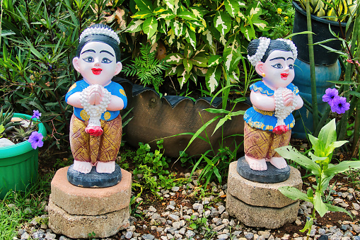 Low Sak, Thailand, June 16, 2022. Traditional Thai garden ornaments: statuettes of smiling girls in a welcoming pose in a garden in Lom Sak, Thailand