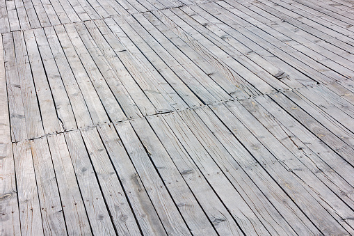 Closeup of a sun-bleached grey hardwood deck floor.