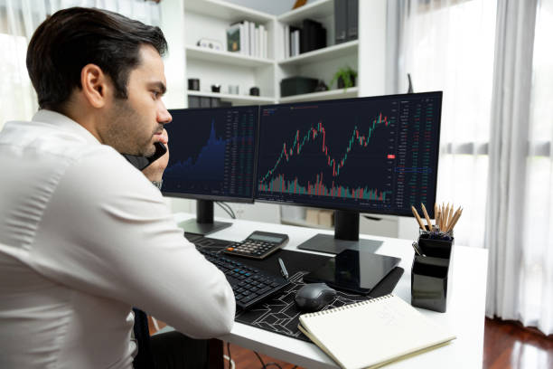 istock Trader calling to consultant or partner with two stock exchange screen. Surmise. 2148176656