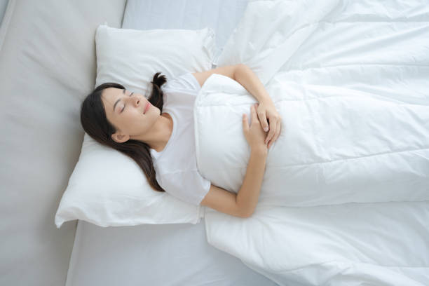 istock Young woman sleeping in a comfortable white bedroom. 2148176953
