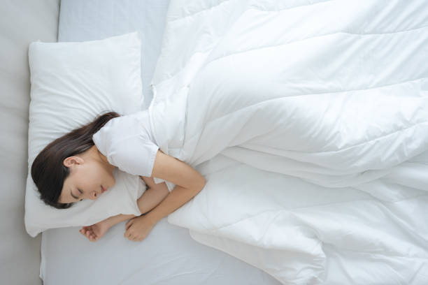 istock Young woman sleeping in a comfortable white bedroom. 2148176971