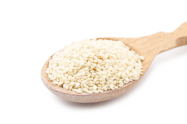 istock Sesame seeds in wooden spoon isolated on white background 2148177027
