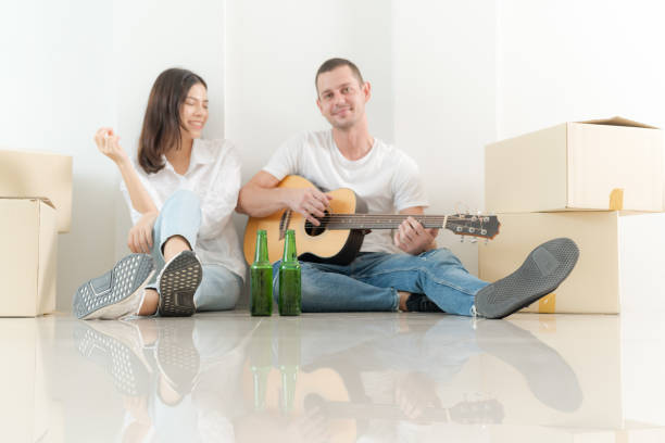 The two young people sat on the floor between the cardboard boxes, relaxed, happy expressions on their faces.
