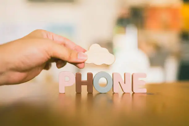 Photo of A hand holding a symbol of a cloud with text PHONE, which indicates the cloud computing system.