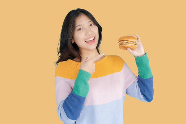 istock Beautiful young woman smiling happily while holding burger in her hand 2148179844