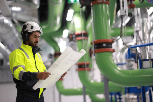 istock Male Industrial Engineers working with Project Blueprints drawing at front heavy industrial machinery, HVAC system engineer 2148180543