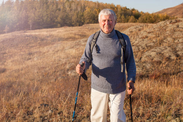 istock Attractive gray haired senior man hiking in forest using poles for nordic walking 2148182026