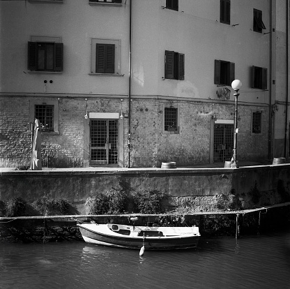 A fishing boat in a water canal in Leghorn in Tuscany, shot with black and white film