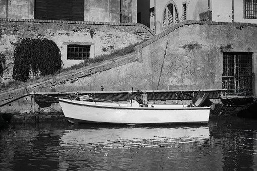 A fishing boat in a water canal in Leghorn in Tuscany, shot with black and white film