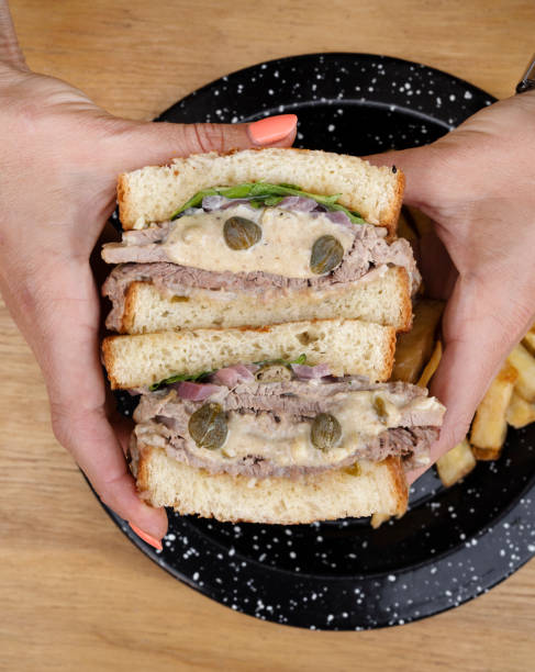 A woman holding a vitel tone meat sandwich