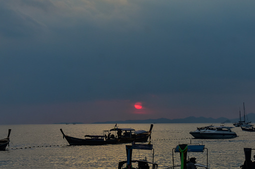 Sunset near Reilly Beach of Krabi with long tail boats in sea .