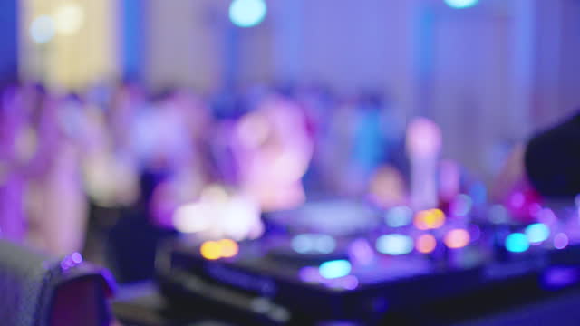 Defocused DJ Works with Mixer in a Nightclub