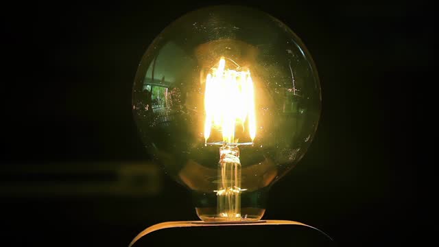 Electric Light Bulb Being Turned Off in Dark Room. Close Up. 4K Resolution.