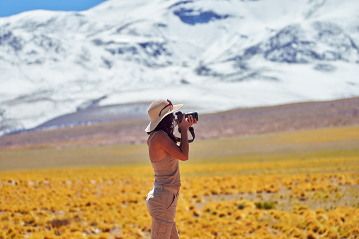 traveler woman taking pictures in the altiplano Los Flamencos National Reserve, San Pedro de Atacama Antofagasta Region