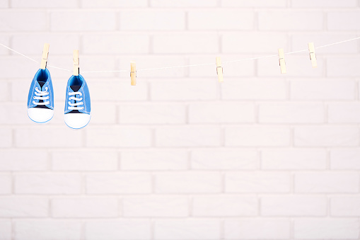 Baby shoes hanging on brick wall background