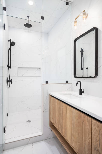 A bathroom with a floating wood cabinet and white marble tiled shower.