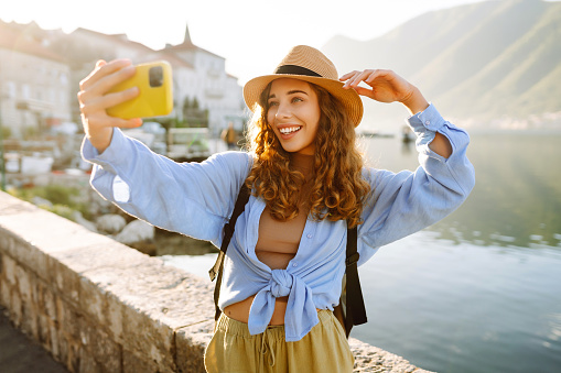 Beautiful tourist walks the streets and takes selfie using smartphone camera. Lifestyle, travel, rest, weekend, active life.