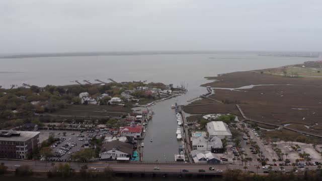 Aerial wide reverse pullback shot of Shem Creek on a hazy day in Mount Pleasant, South Carolina. 4K