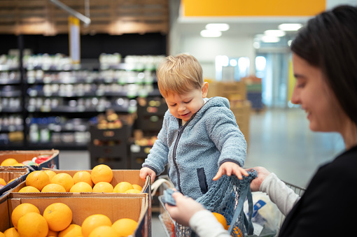 Young mother and toddler shopping for groceries at a supermarket.
