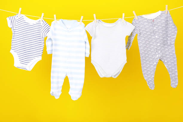 istock Baby clothes hanging on yellow background 2148187656