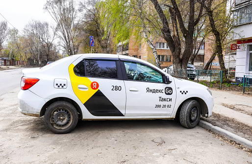 Samara, Russia - April 12, 2023: Yandex Taxi cab is parked on a city street in summer