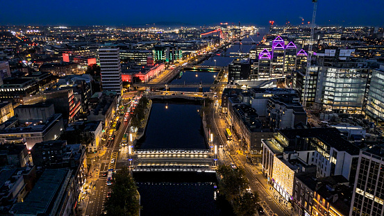 Aerial view of busy city center buildings and traffic at night, Aerial view of the river Liffey and city center Dublin Ireland at night, Aerial view of Dublin skyline and Samuel Beckett Bridge, Aerial view of Dublin city at night, Ireland

Dublin, pronounced is the capital and largest city of Ireland. On a bay at the mouth of the River Liffey, it is in the province of Leinster, bordered on the south by the Dublin Mountains, a part of the Wicklow Mountains range. At the 2016 census it had a population of 1,173,179, while the preliminary results of the 2022 census recorded that County Dublin as a whole had a population of 1,450,701, and that the population of the Greater Dublin Area was over 2 million, or roughly 40% of the Republic of Ireland's total population.