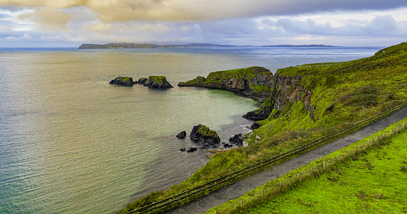 Aerial view of two islands with Carrick-a-Rede Rope Bridge in Northern Ireland, Carrick-a-Rede Rope Bridge connecting two islands in Ireland, Rope bridge connecting two cliffs in Northern Ireland, Carrick-a-Rede Rope Bridge\n\nThe Carrick-a-Rede Rope Bridge (locally pronounced carrick-a-reed) is a rope bridge near Ballintoy in County Antrim, Northern Ireland. The bridge links the mainland to the tiny island of Carrickarede (from Irish Carraig a' Ráid, meaning 'rock of the casting'). It spans 20 metres (66 ft) and is 30 metres (98 ft) above the rocks below. The bridge is mainly a tourist attraction and is owned and maintained by the National Trust. In 2018, the bridge had 485,736 visitors. The bridge is closed for winter (subject to weather) and people may cross it for a fee.