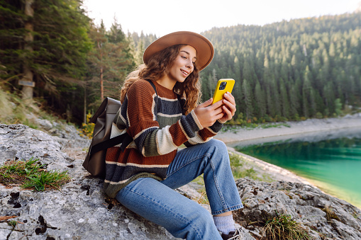 Young woman tourist uses a smartphone on the nature. Lifestyle, travel, tourism, active life.