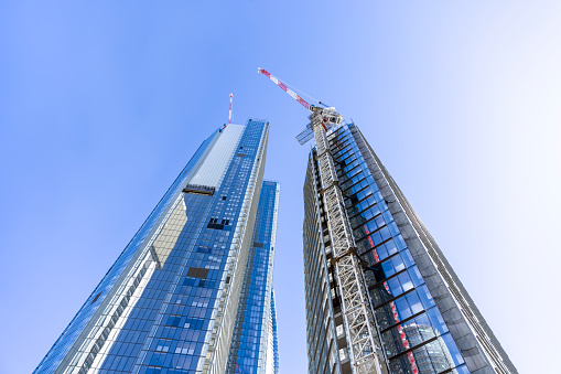 The construction of a multi-storey building. Two construction cranes on a building construction. Scaffolding on several floors.