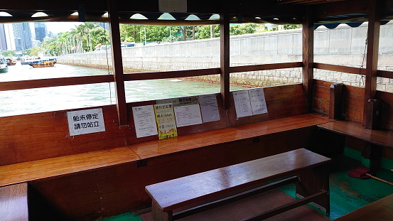 Hong Kong - 07.11.2021: Interior of an empty kaito, traditional motorised ferry, with wooden benches in Pontoon outside Marina Habitat in Aberdeen West Typhoon Shelter on a sunny day