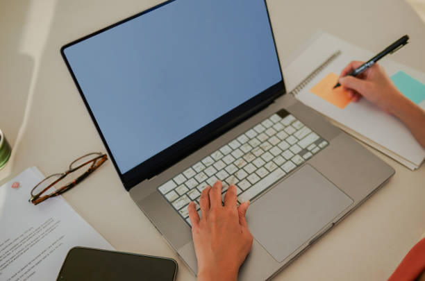 istock High angle view of woman working on laptop and writing notes at work desk 2148191637