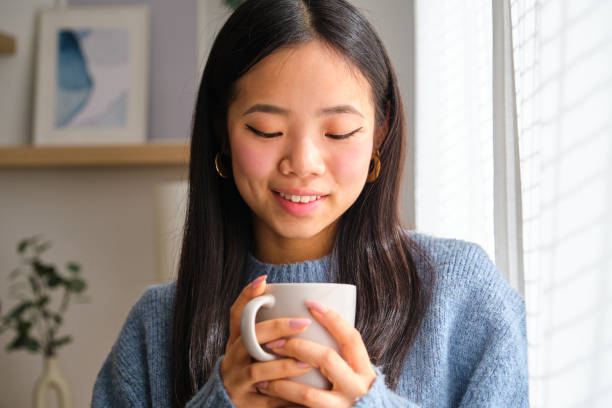istock Asian woman is holding a mug and smiling. 2148192092